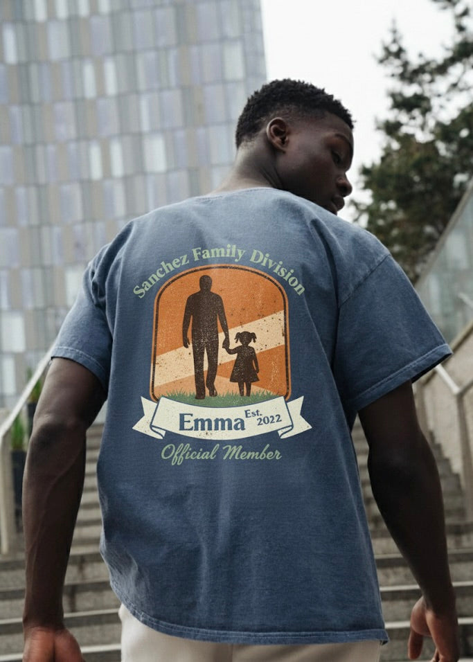 Person wearing a blue t-shirt with a graphic design on the back, standing outdoors.