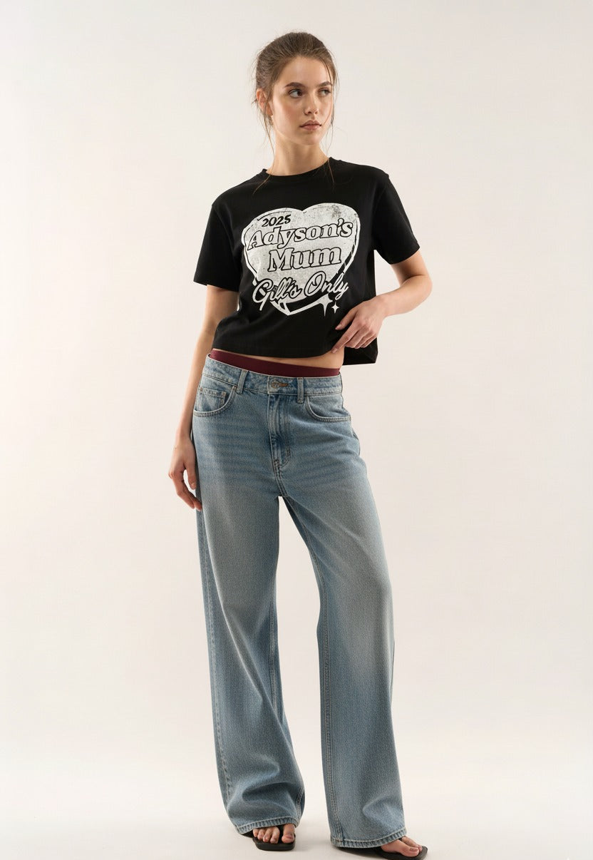 Woman wearing a black t-shirt with text and light blue jeans on a white background